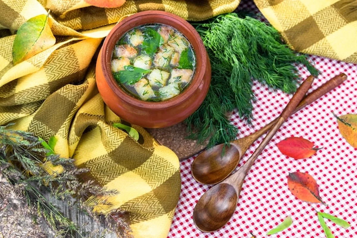 Gliniany garnek z zupą na drewnianym stole