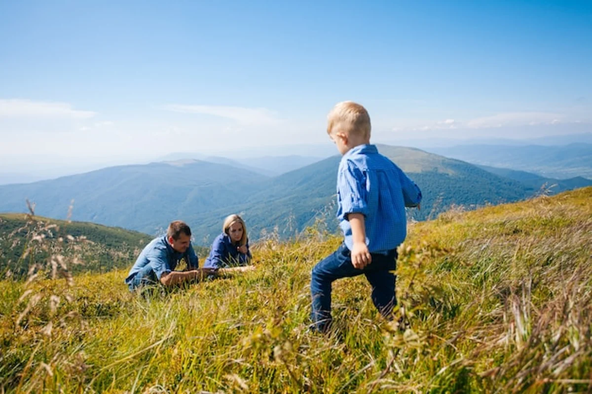 Szczęśliwa młoda rodzina zbierająca jagody w górach