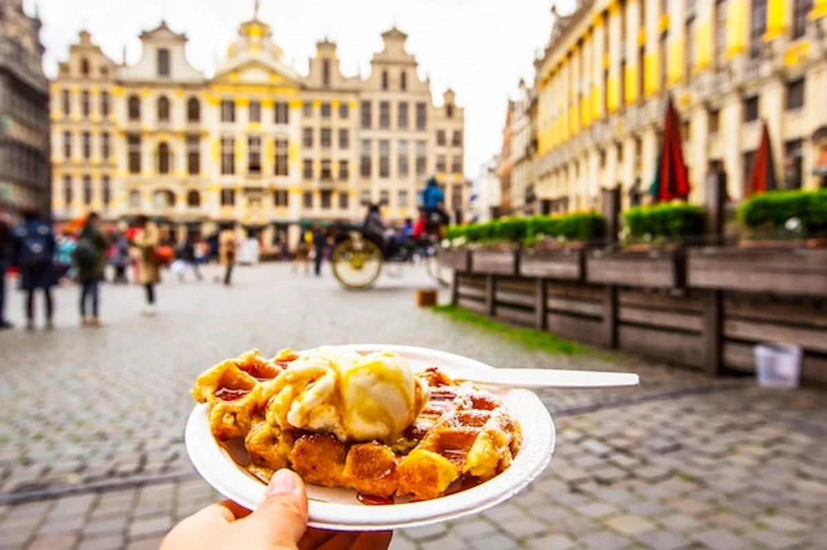 Belgijskie gofry z lodami na talerzu na tle Grote Markt w Brukseli