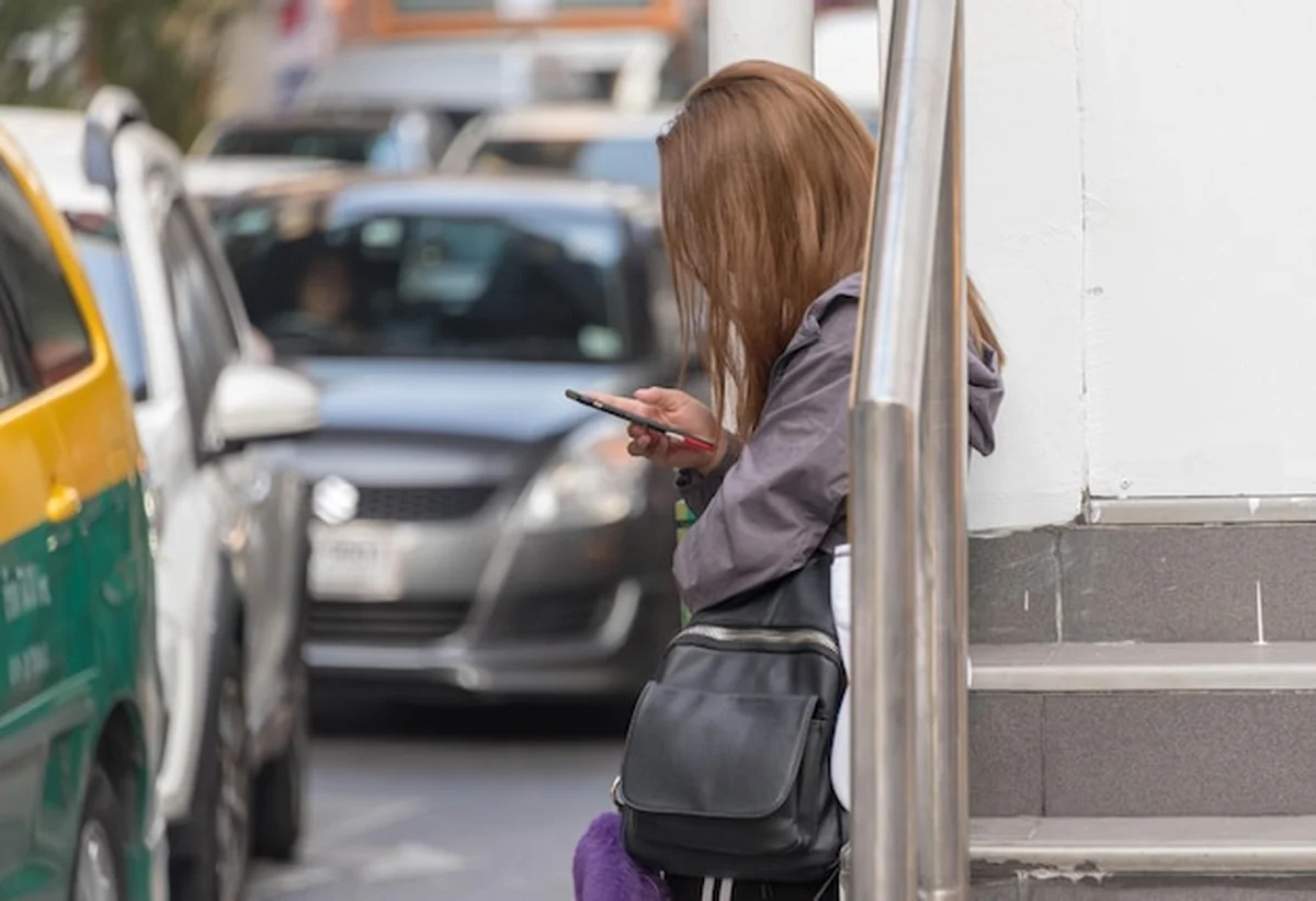 Kobieta używająca telefonu na przystanku autobusowym