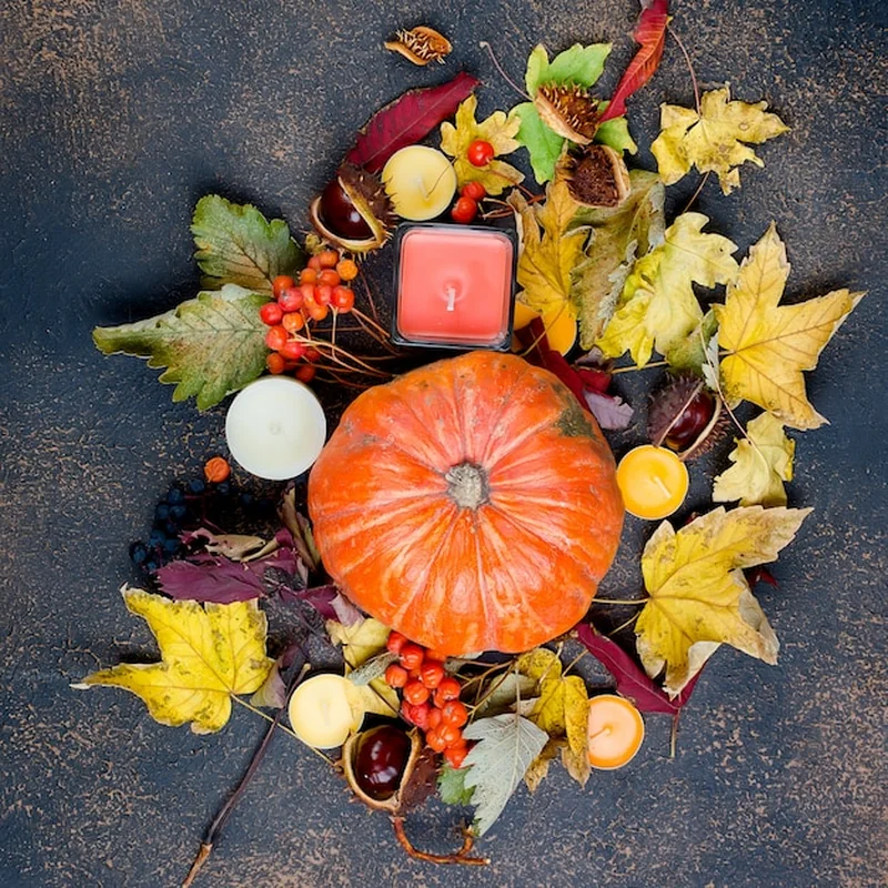 Jesienne liście, dynia, kasztany, świece na ciemnym tle