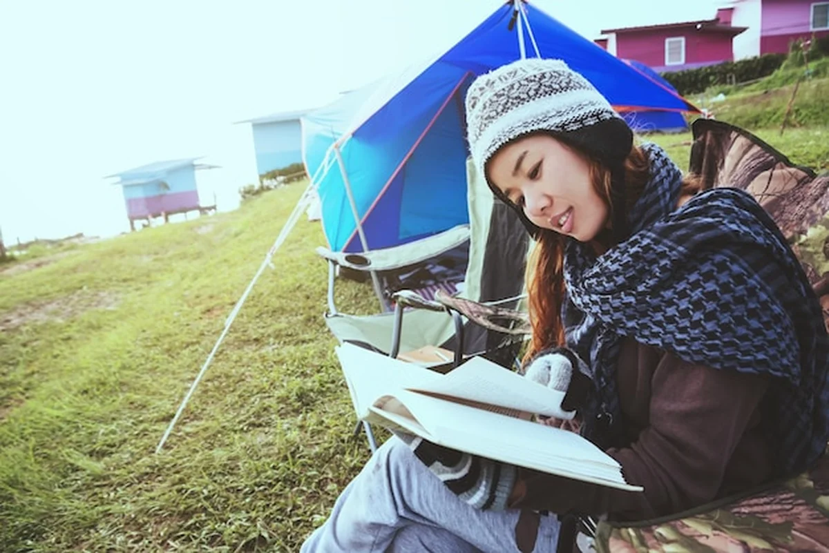 Kobieta czyta książkę na kempingu